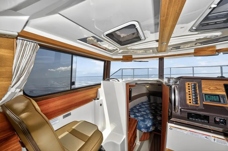 Slide: The Image of 2024 Ranger Tugs R-27 interior with helm, seating, and cabin view. - 37