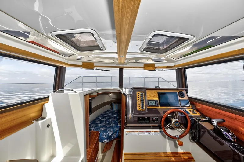 Slide: The Image of 2024 Ranger Tugs R-27 interior with modern helm and cozy cabin view. - 38