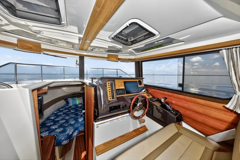 Slide: The Image of 2024 Ranger Tugs R-27 interior with helm, navigation equipment, and cozy cabin view. - 39