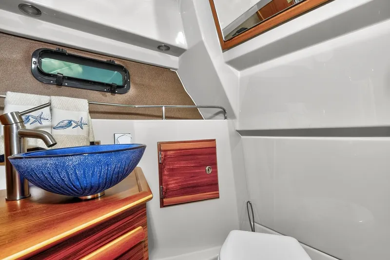 Slide: The Image of 2024 Ranger Tugs R-27 bathroom with blue vessel sink and nautical decor. - 40