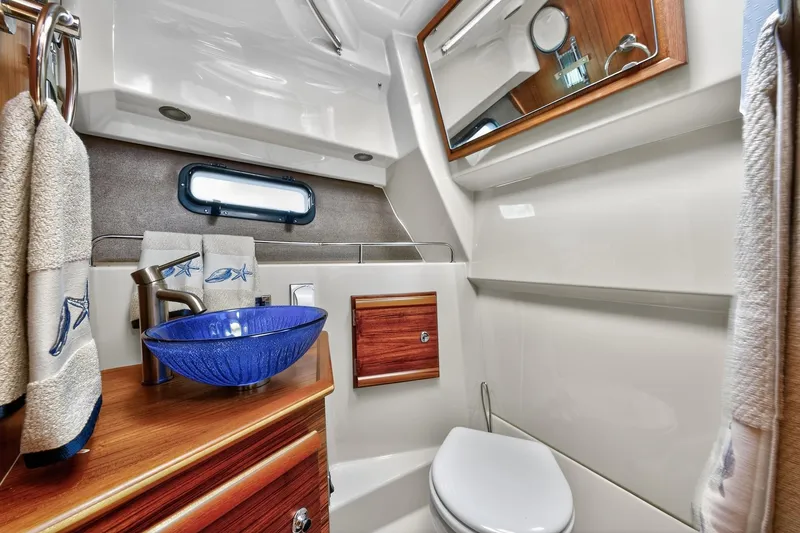 Slide: The Image of 2024 Ranger Tugs R-27 bathroom with blue glass sink and wooden accents. - 41