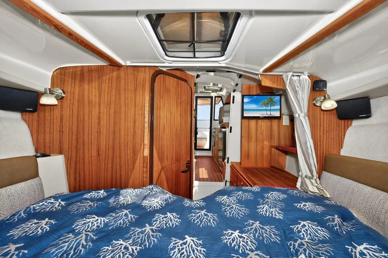 Slide: The Image of 2024 Ranger Tugs R-27 interior cabin with wood paneling, bed, and TV. - 42