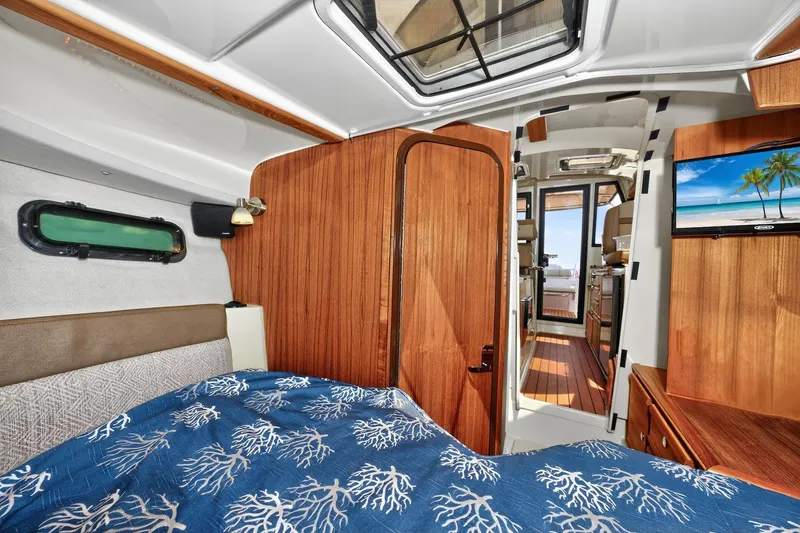 Slide: The Image of 2024 Ranger Tugs R-27 interior cabin with wood paneling and cozy bedding. - 43