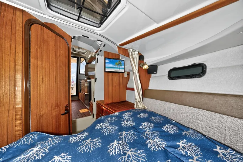 Slide: The Image of 2024 Ranger Tugs R-27 interior cabin with wood accents and cozy bedding. - 44