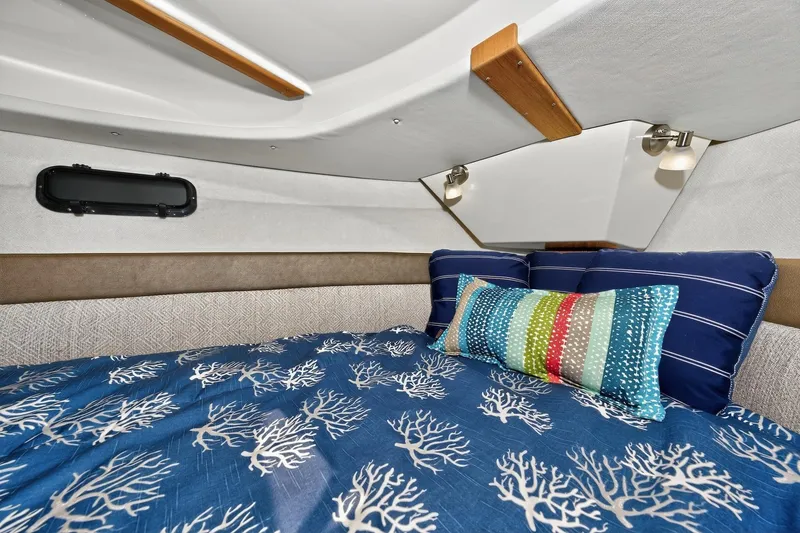 Slide: The Image of 2024 Ranger Tugs R-27 cabin interior with nautical-themed bedding and colorful pillows. - 45