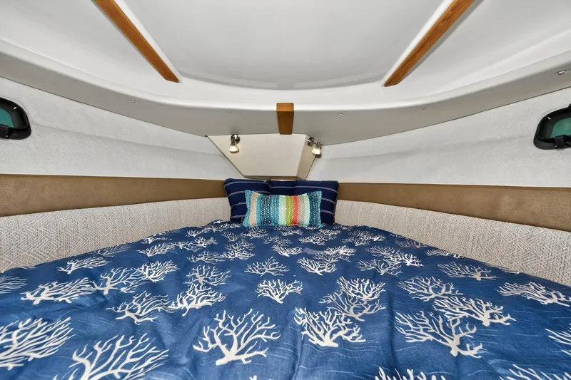 Slide: The Image of 2024 Ranger Tugs R-27 cabin interior with cozy bedding and decorative pillows. - 47