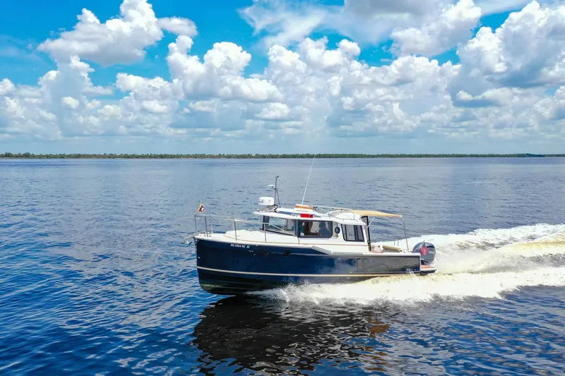 Slide: The Image of 2024 Ranger Tugs R-27 cruising on a serene lake under a vibrant blue sky. - 5