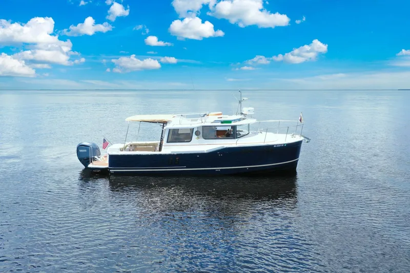 Slide: The Image of 2024 Ranger Tugs R-27 boat on calm water under a clear blue sky. - 8