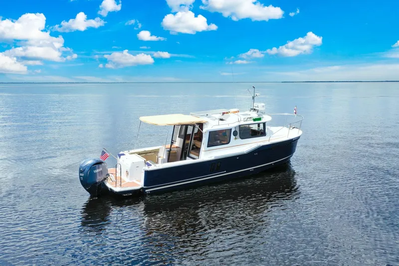 Slide: The Image of 2024 Ranger Tugs R-27 boat on calm water under a clear blue sky. - 9