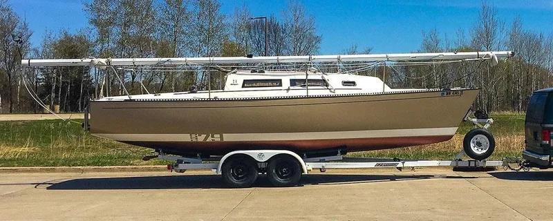 Slide: The Image of 1982 S2 7.9 sailboat on trailer, parked outdoors with trees in background. - 11