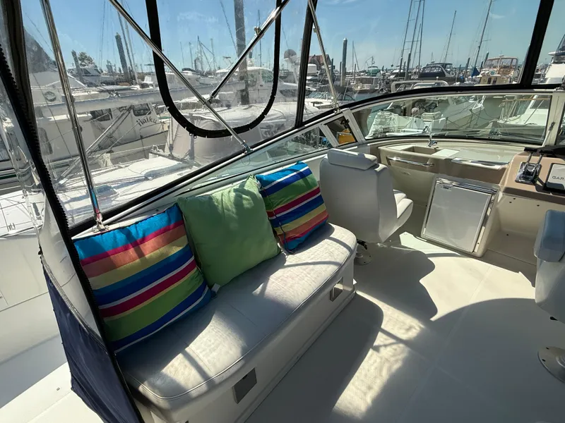 Slide: The Image of 2006 Carver 36 Mariner interior with colorful cushions and helm station in marina setting. - 10