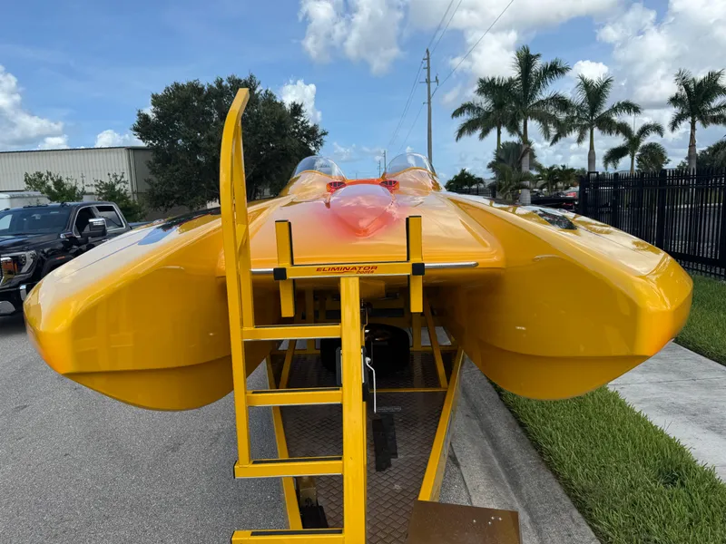 Slide: The Image of 2006 Eliminator 33 Daytona powerboat in vibrant yellow, parked on a trailer under a sunny sky. - 12