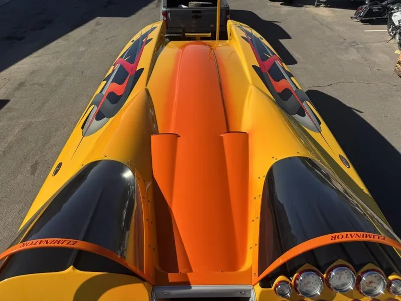Slide: The Image of 2006 Eliminator 33 Daytona speedboat with vibrant orange and yellow design, parked on pavement. - 31