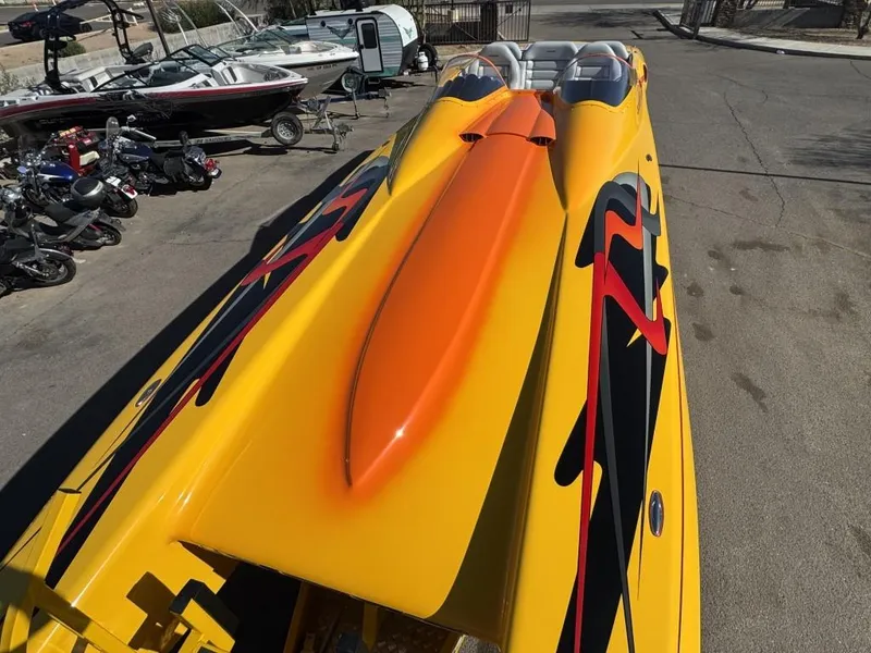 Slide: The Image of 2006 Eliminator 33 Daytona speedboat with vibrant yellow and orange design, parked near other boats. - 33