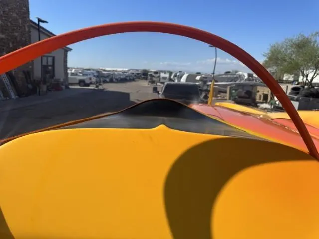 Slide: The Image of 2006 Eliminator 33 Daytona boat with vibrant orange and yellow design in a storage area. - 35