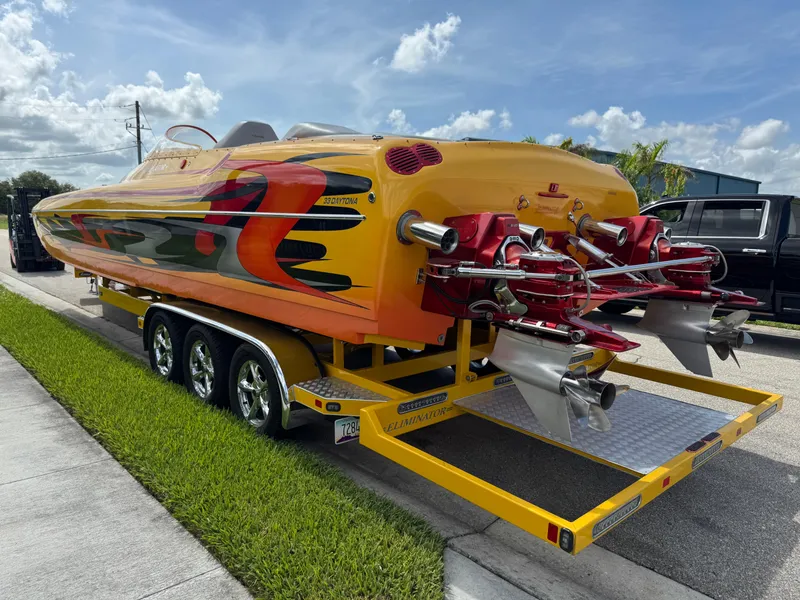 Slide: The Image of 2006 Eliminator 33 Daytona speedboat on trailer, vibrant orange and red design, dual propellers. - 5