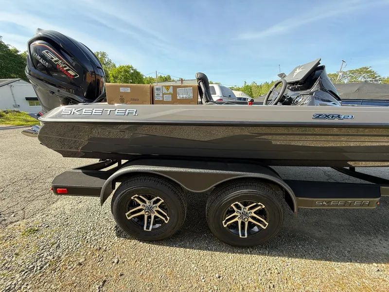 Slide: The Image of 2025 Skeeter ZXR21 boat on trailer with Yamaha engine, parked outdoors. - 12