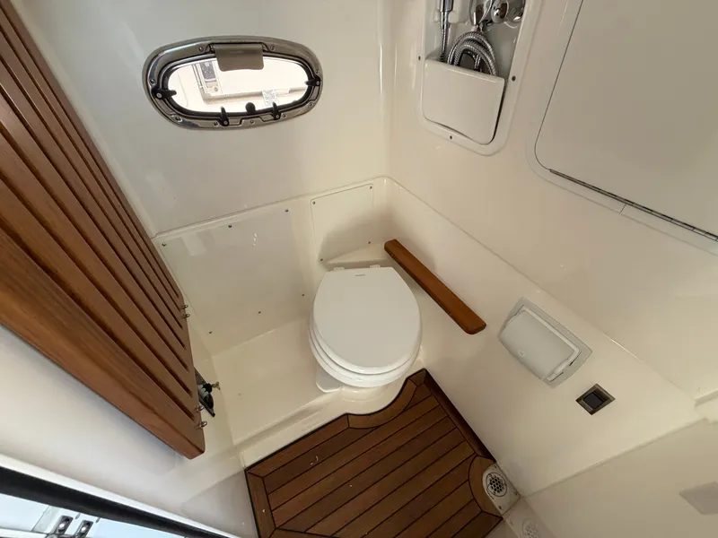 Slide: The Image of The 2026 Boston Whaler 380 Outrage cabin features a toilet and wooden flooring. - 35