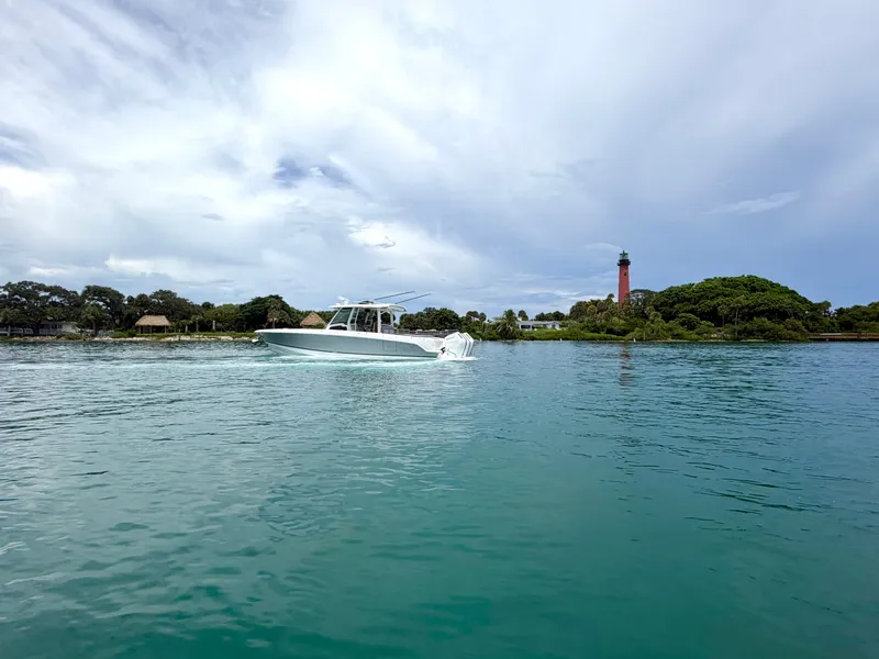 Slide: The Image of 2026 Boston Whaler 380 Outrage on calm water with a lighthouse in the background. - 14