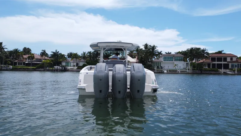 Slide: The Image of A 2027 Boston Whaler 380 Outrage with three outboard engines on calm water near a shoreline. - 7