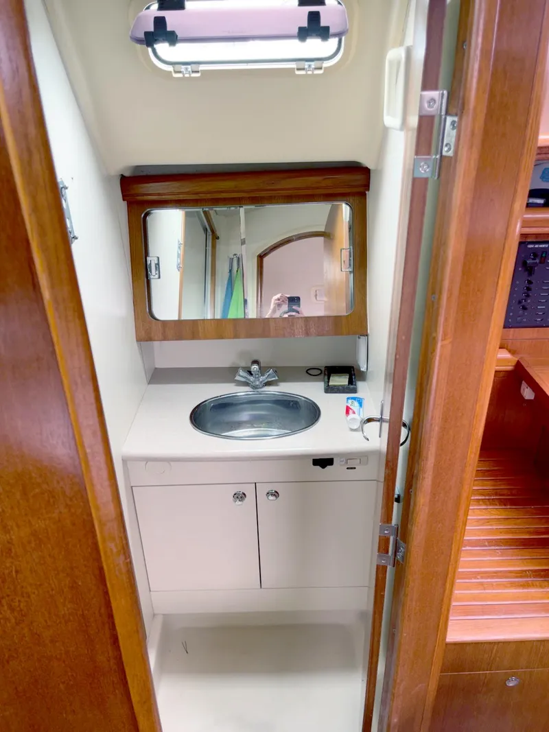 Slide: The Image of Compact bathroom in 2005 Hunter 38 sailboat with sink, mirror, and wooden cabinetry. - 12