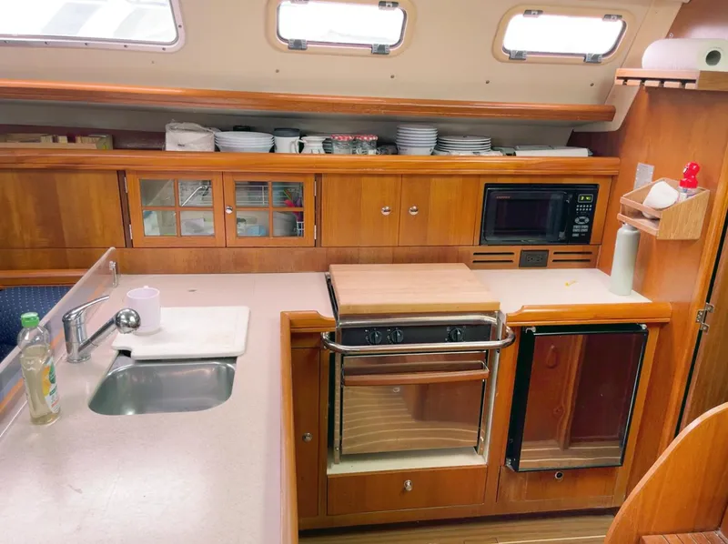 Slide: The Image of 2005 Hunter 38 yacht kitchen with wooden cabinets, sink, stove, and microwave. - 4