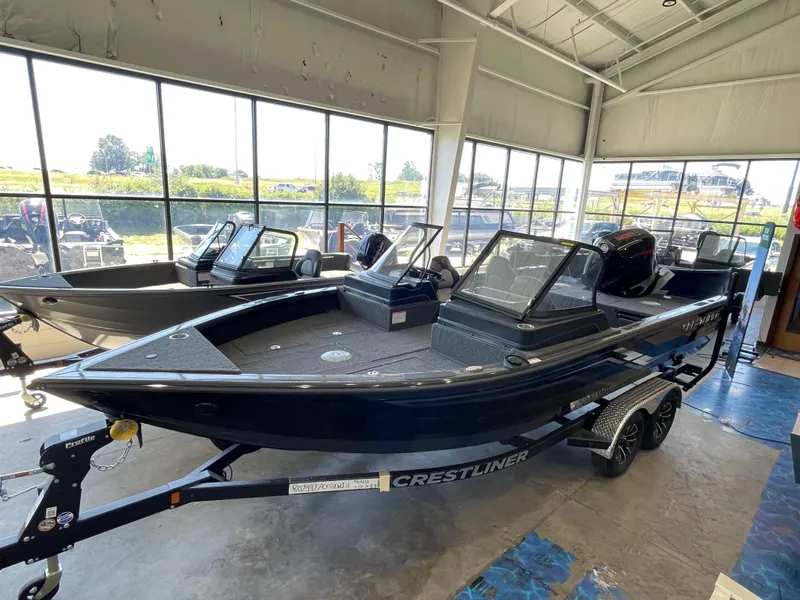 Slide: The Image of 2025 Crestliner 2050 Fish Hawk boat displayed in a showroom, featuring sleek design and modern amenities. - 1