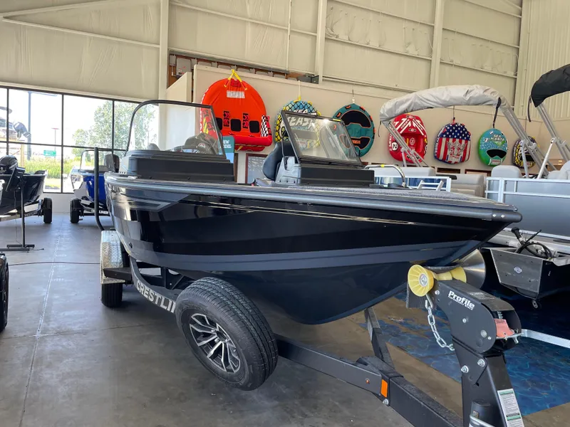 Slide: The Image of 2025 Crestliner 2050 Fish Hawk boat displayed in showroom, featuring sleek black design. - 3