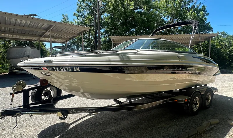 Slide: The Image of 2007 Crownline 220 LS boat on trailer, parked under a canopy, surrounded by trees. - 14