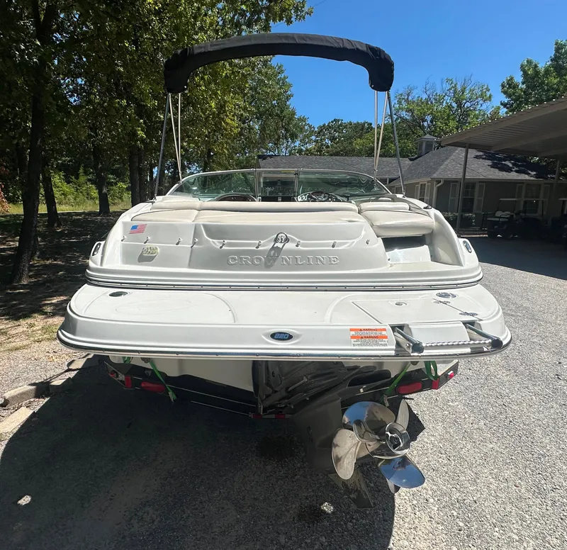 Slide: The Image of 2007 Crownline 220 LS boat parked outdoors, rear view with trees and house in background. - 3
