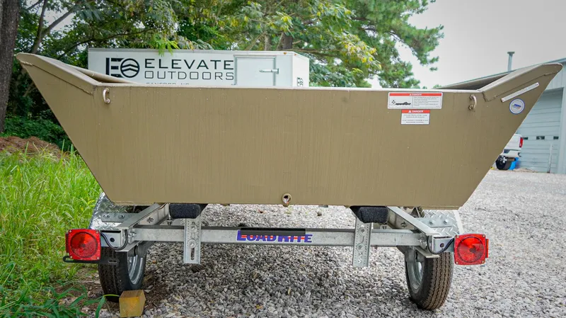 Slide: The Image of Trailer with G3 1548 VBW boat, 2025 model, parked on gravel near trees. - 2