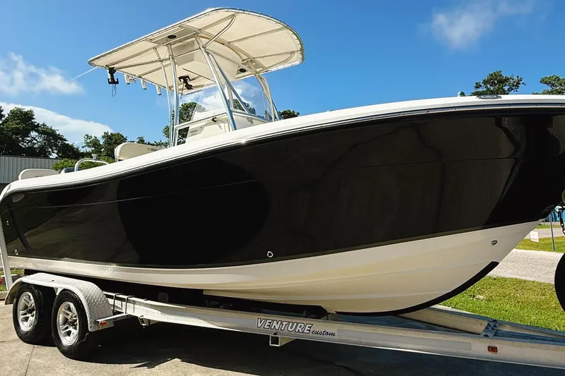 Slide: The Image of 2012 Cobia 217 Center Console boat on trailer, black hull, sunny day. - 0