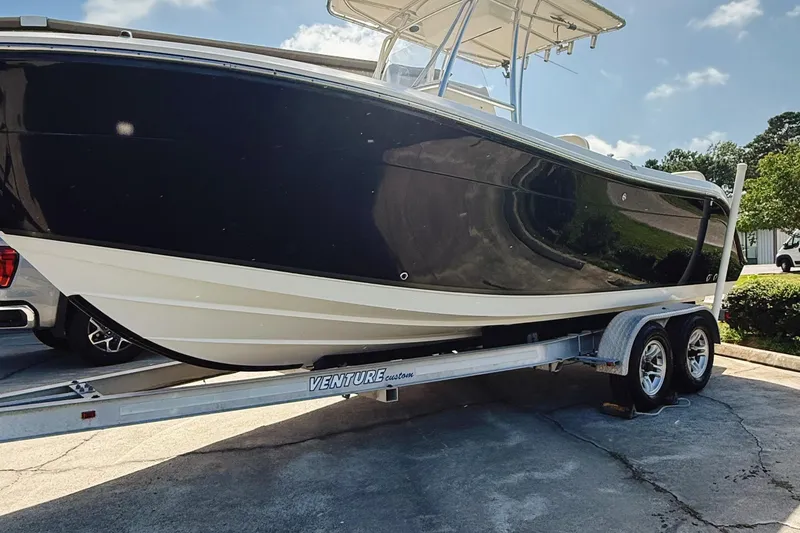 Slide: The Image of 2012 Cobia 217 Center Console boat on a Venture trailer, parked outdoors. - 1