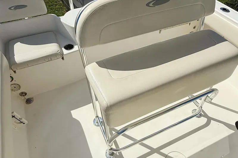 Slide: The Image of 2012 Cobia 217 Center Console boat interior with cushioned seating and stainless steel fixtures. - 12