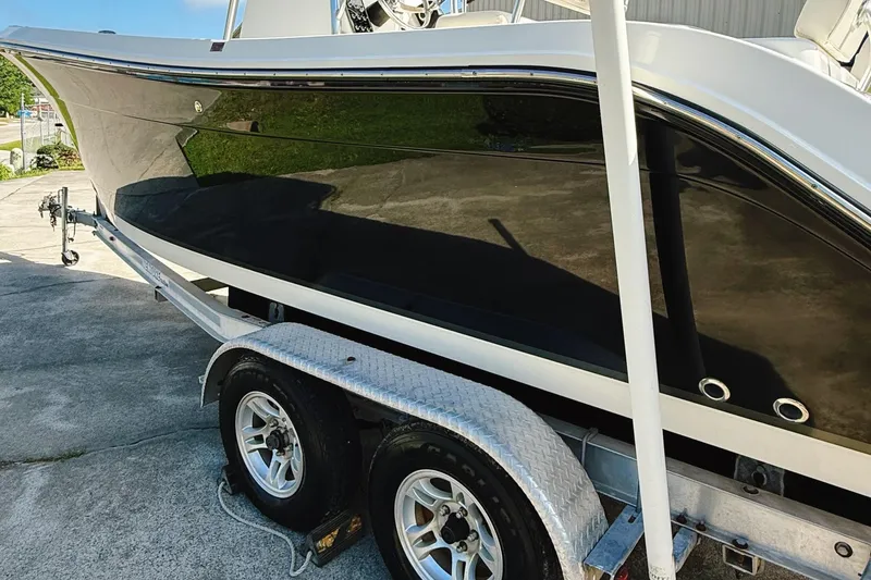 Slide: The Image of 2012 Cobia 217 Center Console boat on trailer, black hull, parked outdoors. - 2