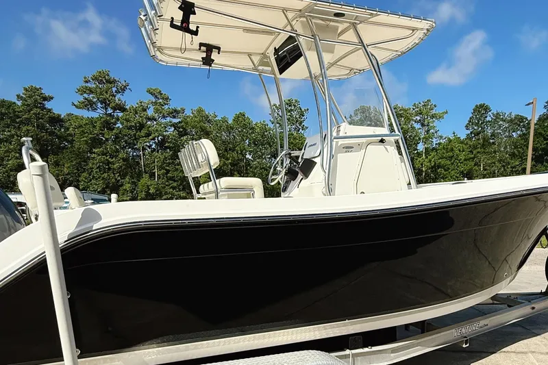 Slide: The Image of 2012 Cobia 217 Center Console boat on trailer, black hull, clear sky background. - 3