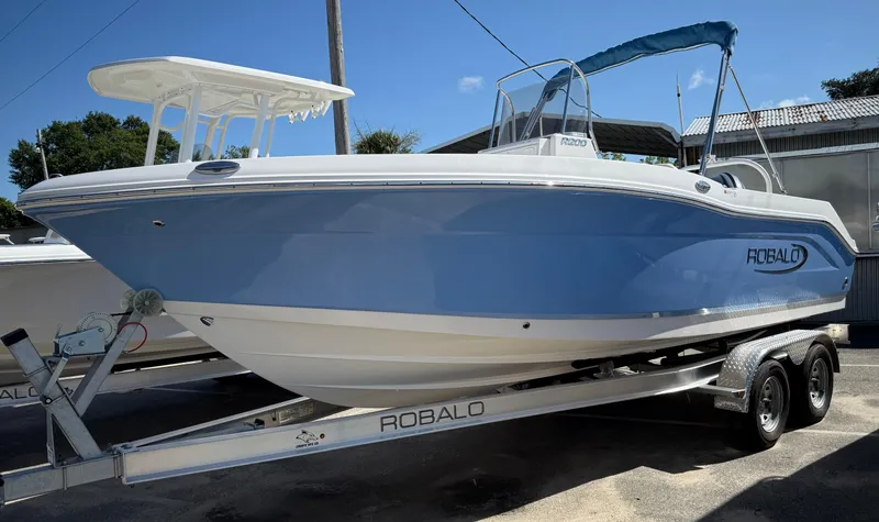 The Image of 2025 Robalo R200 Center Console boat on trailer, light blue hull, outdoor display. - 0