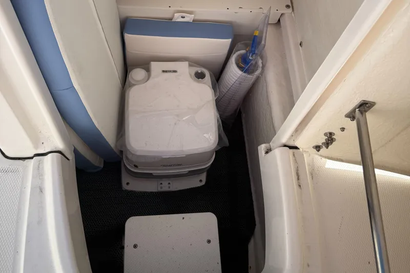 Slide: The Image of 2025 Robalo R200 Center Console boat interior with portable toilet and storage area. - 11