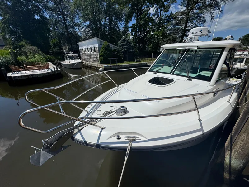 Slide: The Image of 2019 Boston Whaler 285 Conquest boat docked in a serene, wooded marina. - 25