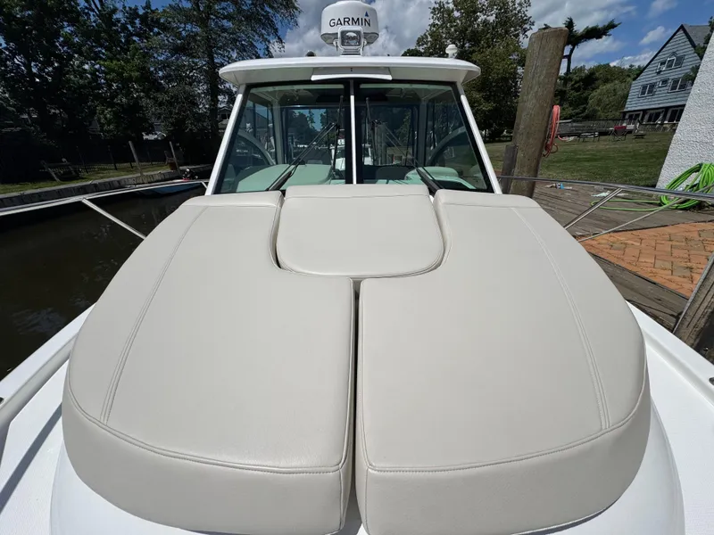 Slide: The Image of 2019 Boston Whaler 285 Conquest boat with cushioned deck, docked near a scenic waterfront. - 26