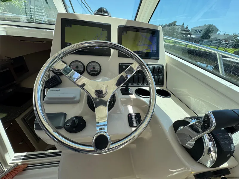 Slide: The Image of 2019 Boston Whaler 285 Conquest helm with steering wheel, navigation screens, and controls. - 35