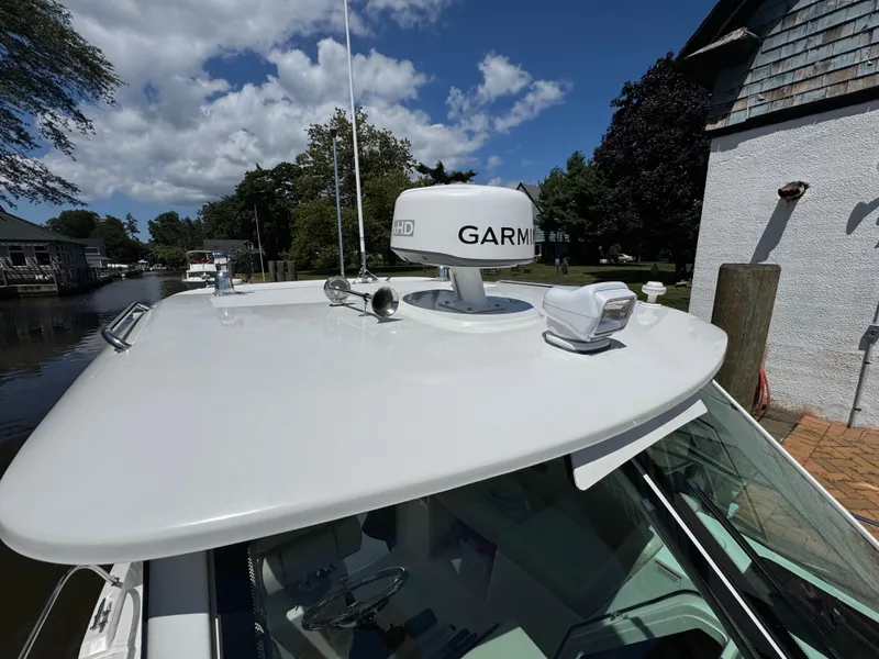Slide: The Image of 2019 Boston Whaler 285 Conquest with Garmin radar, docked under a clear blue sky. - 37