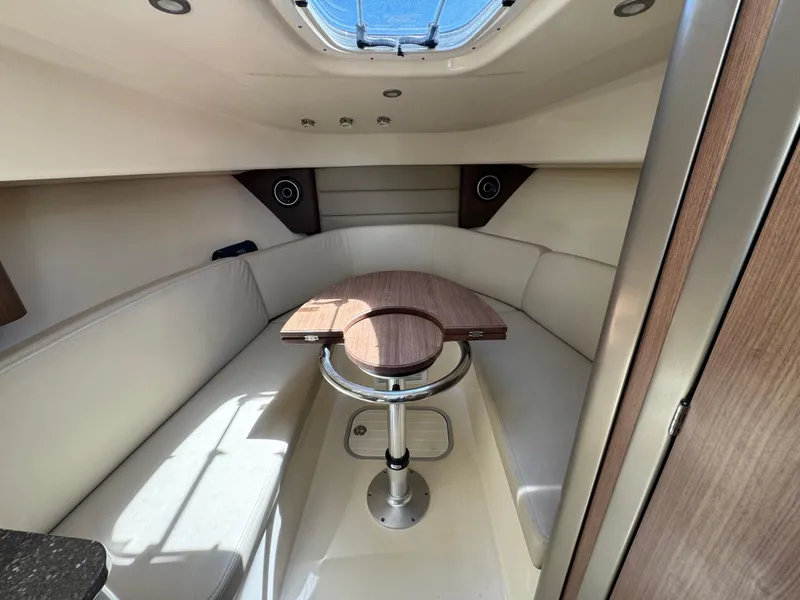 Slide: The Image of 2019 Boston Whaler 285 Conquest cabin interior with seating and wooden table. - 41