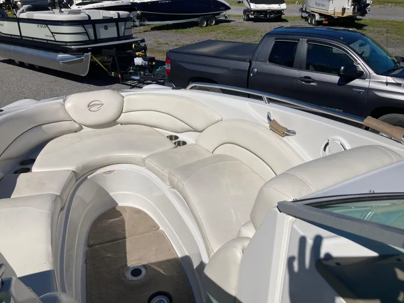 Slide: The Image of 2007 Crownline 260 LS boat interior with white seating, parked near a truck and other boats. - 19