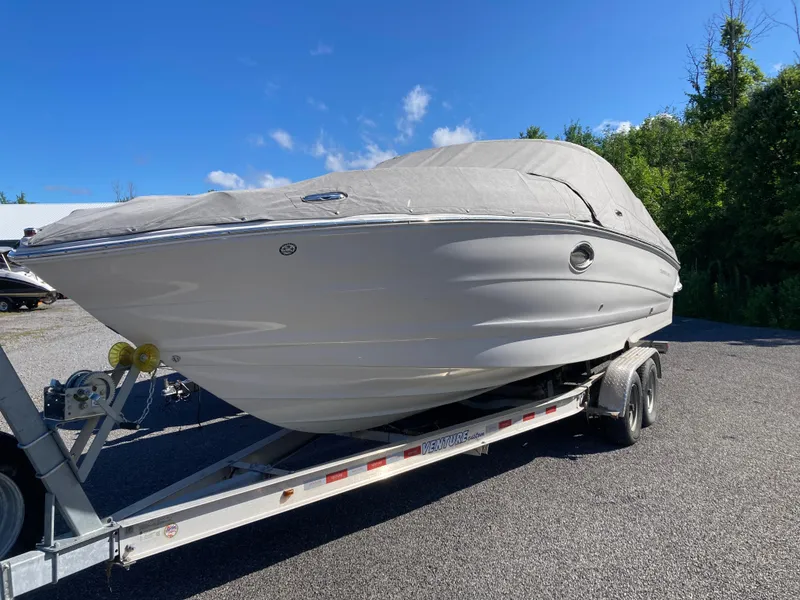 Slide: The Image of 2007 Crownline 260 LS boat on trailer, covered, parked outdoors under clear blue sky. - 3