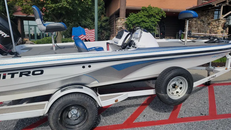 Slide: The Image of 2006 Nitro 482 DC boat on trailer, parked outdoors, featuring blue and white design. - 11