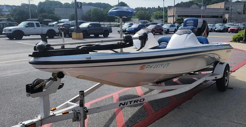 Slide: The Image of 2006 Nitro 482 DC boat on trailer in parking lot, surrounded by vehicles. - 7