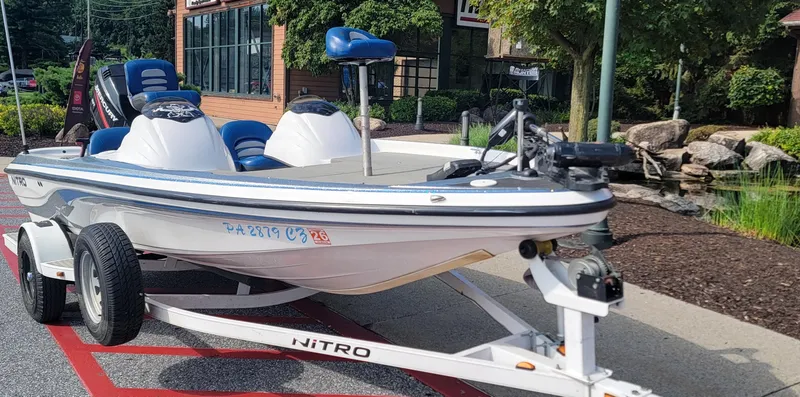 Slide: The Image of 2006 Nitro 482 DC boat on trailer, parked outdoors near a building and landscaped area. - 8