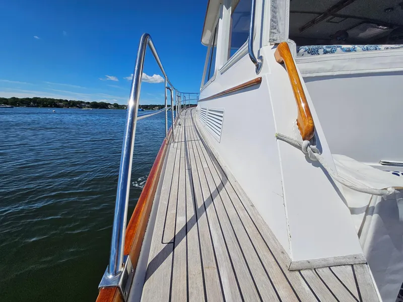 Slide: The Image of 2002 Grand Banks 49 Eastbay HX yacht deck with wooden railings on a sunny day. - 19