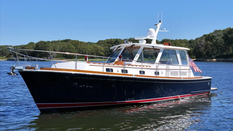 Slide: The Image of 2002 Grand Banks 49 Eastbay HX yacht on calm water, surrounded by lush greenery. - 3